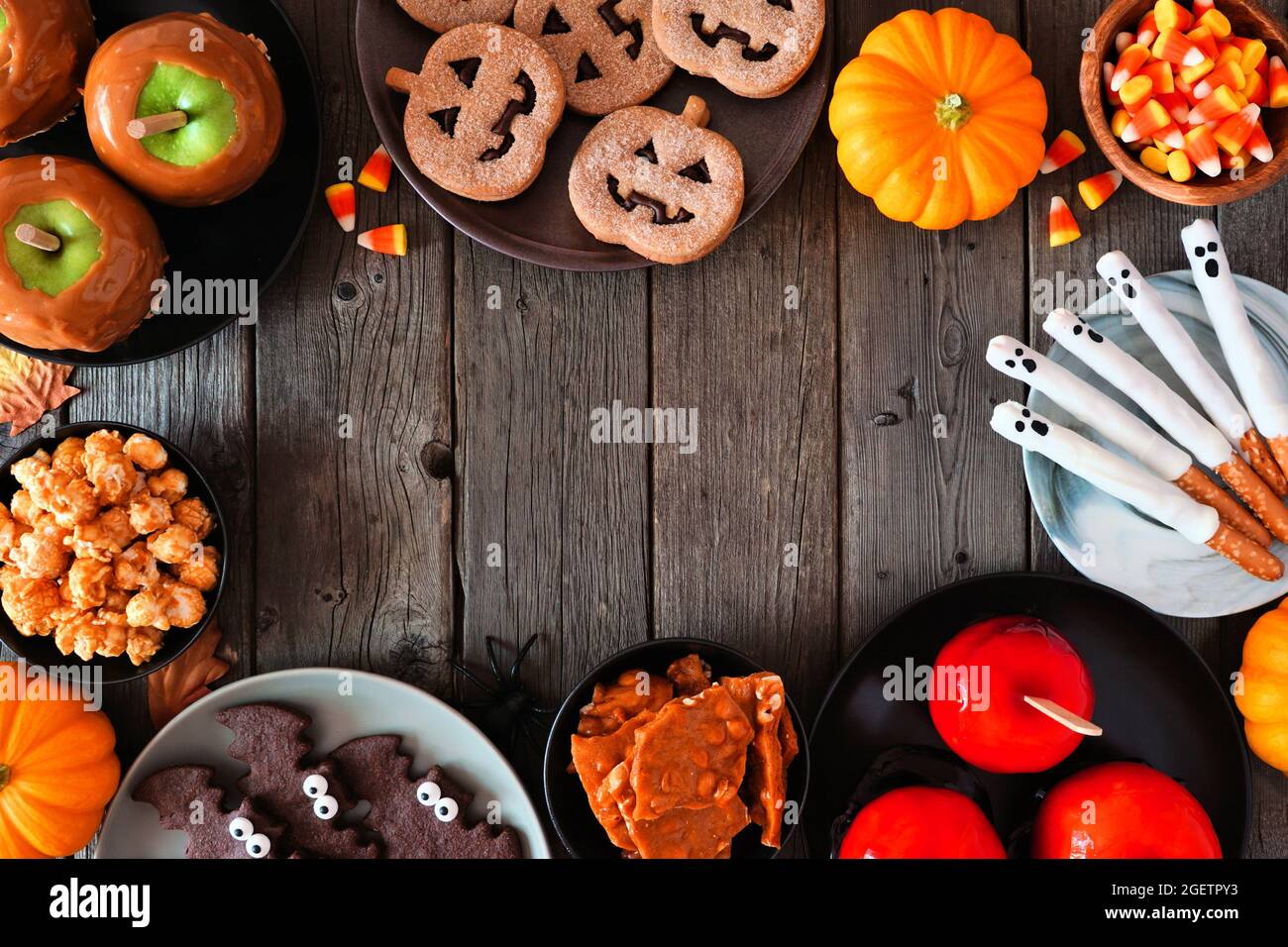 Cornice rustica Halloween trattamento su uno sfondo di legno scuro con spazio copia. Vista dall'alto. Selezione di mele candite, biscotti, caramelle e dolci. Foto Stock