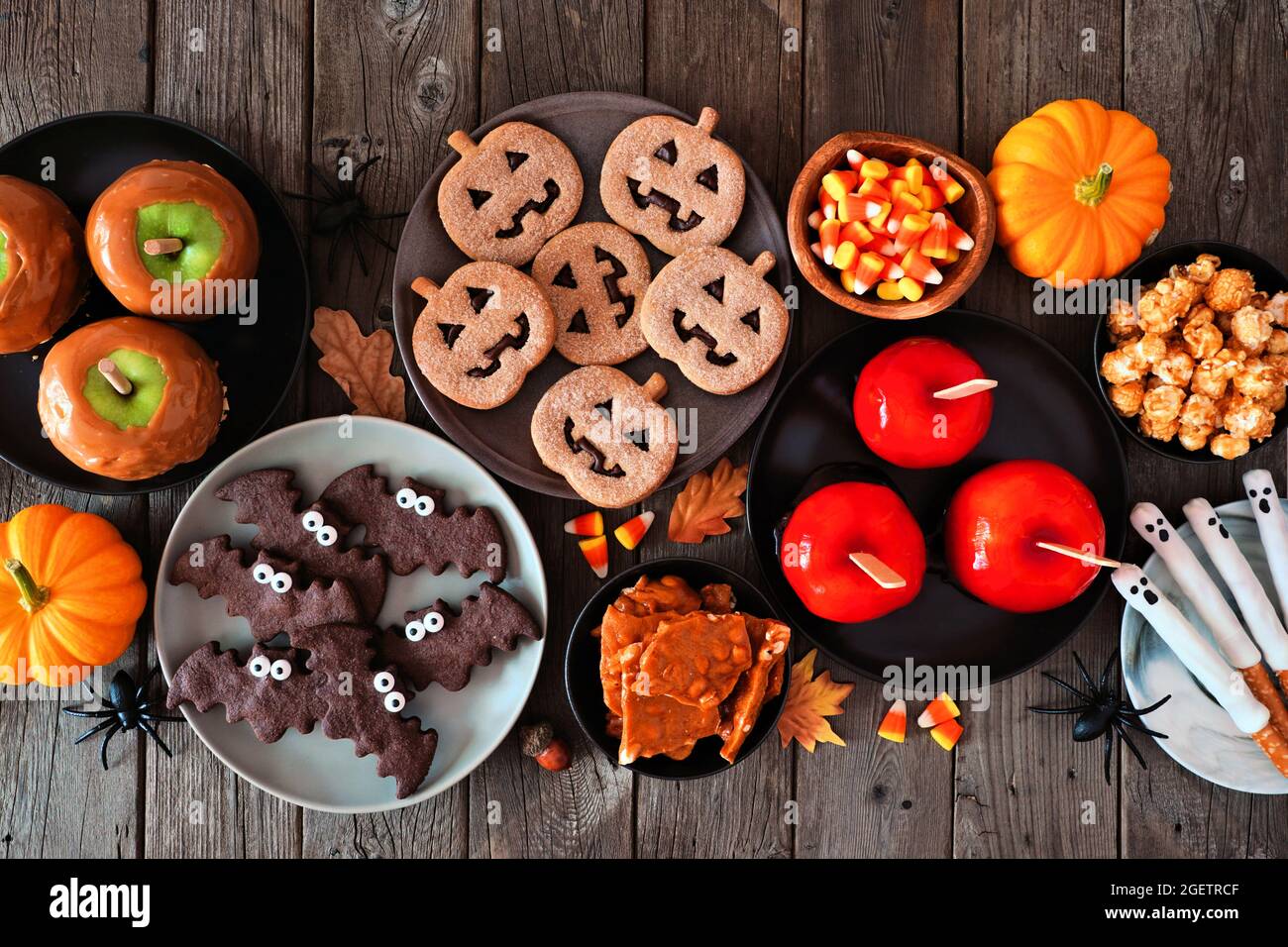 Rustico Halloween trattare scena tabella su uno sfondo di legno scuro. Vista dall'alto. Varietà di mele candite, biscotti, caramelle e dolci. Foto Stock