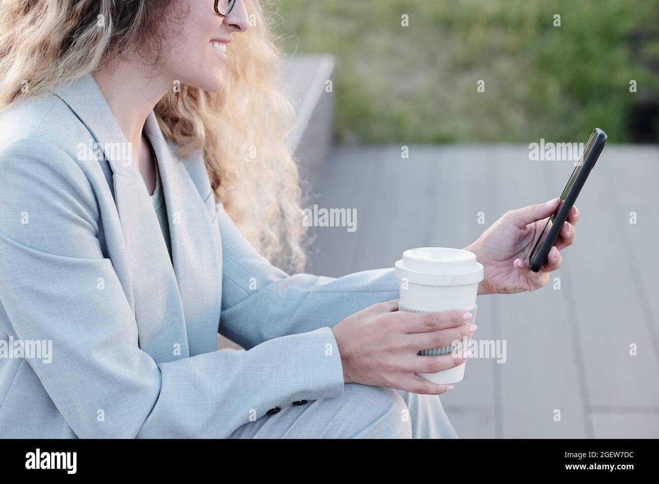 Giovane donna d'affari che scorre nel telefono cellulare e bere a pausa Foto Stock