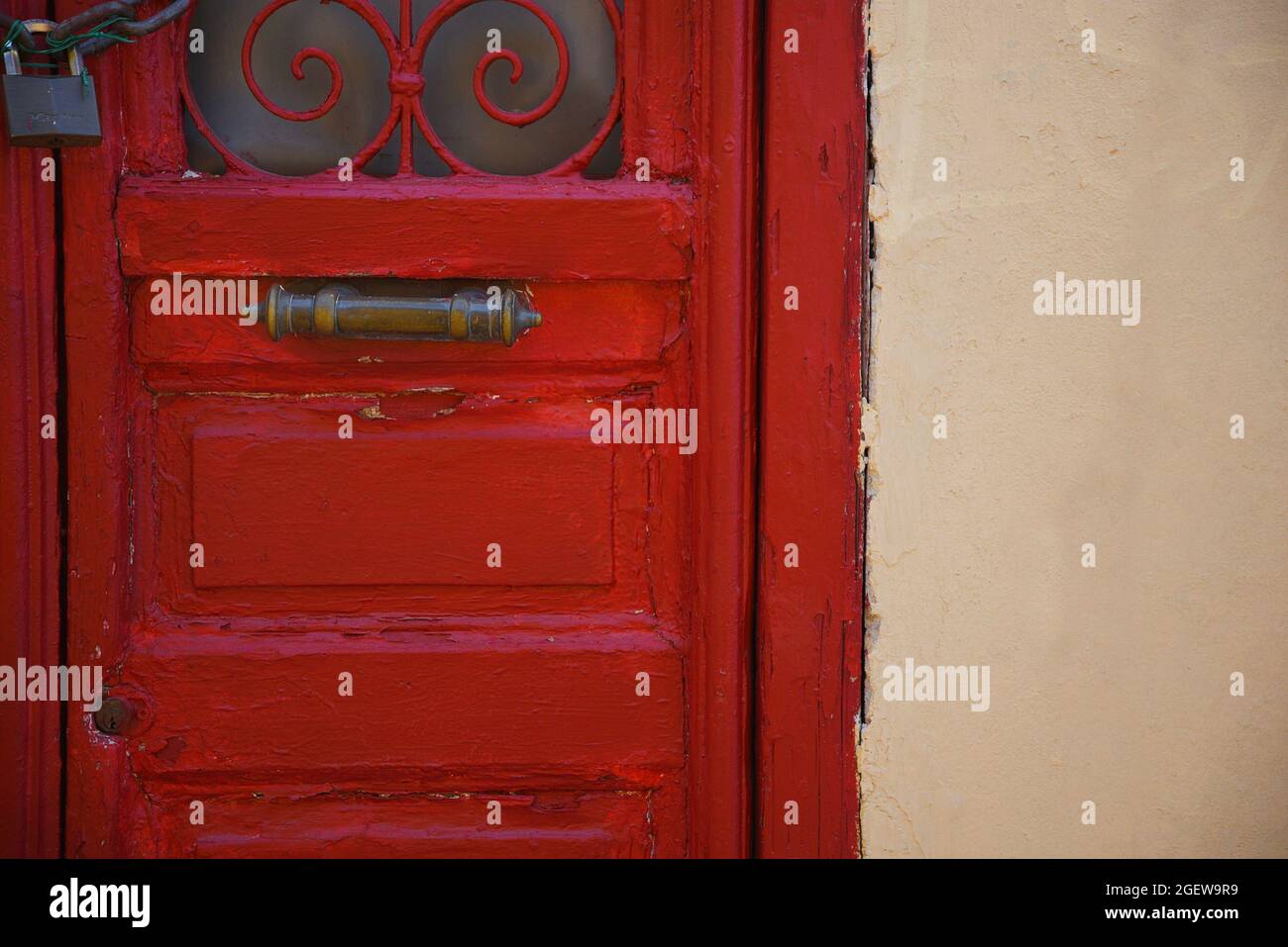 Facciata neoclassica casa con un muro di ocra stucco e una porta di legno rosso con griglie in ferro e un antico manico in ottone Anafiotika Atene Grecia. Foto Stock