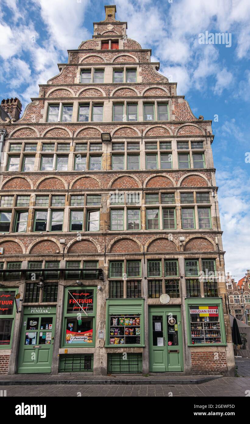 Gent, Fiandre, Belgio - 30 luglio 2021: Casa storica con gable a gradini vende birra belga e patatine fritte in 2 negozi al livello della strada all'angolo con Foto Stock