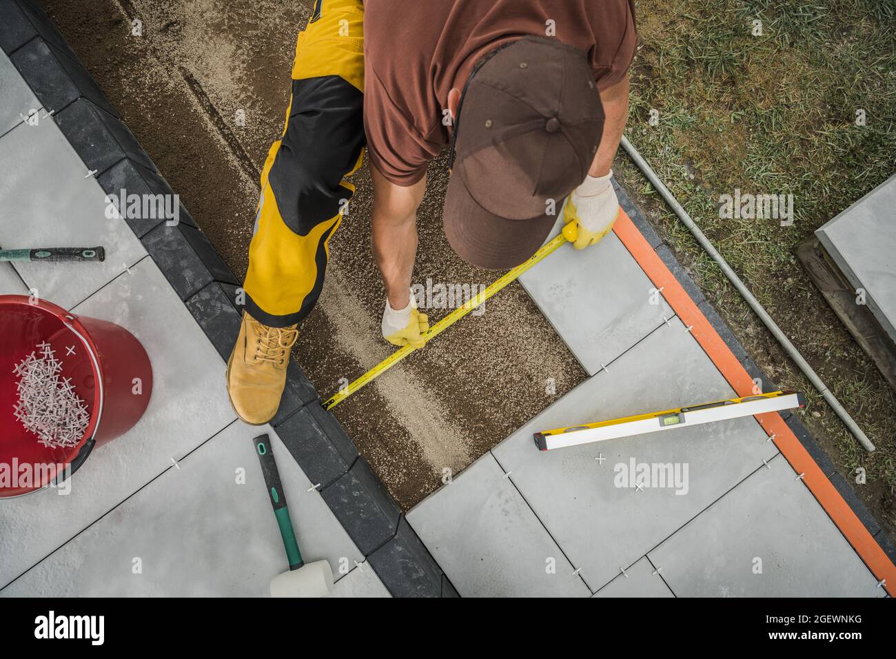 Caucasica piccola architettura lavoratore Paving zona patio residenziale disponendo piastrelle di calcestruzzo esterno. Tema industriale. Foto Stock