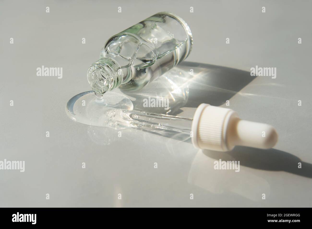 Flacone di gel di acido ialuronico con pipetta su sfondo grigio chiaro. Prodotti alla moda per l'autoproduzione. Foto Stock