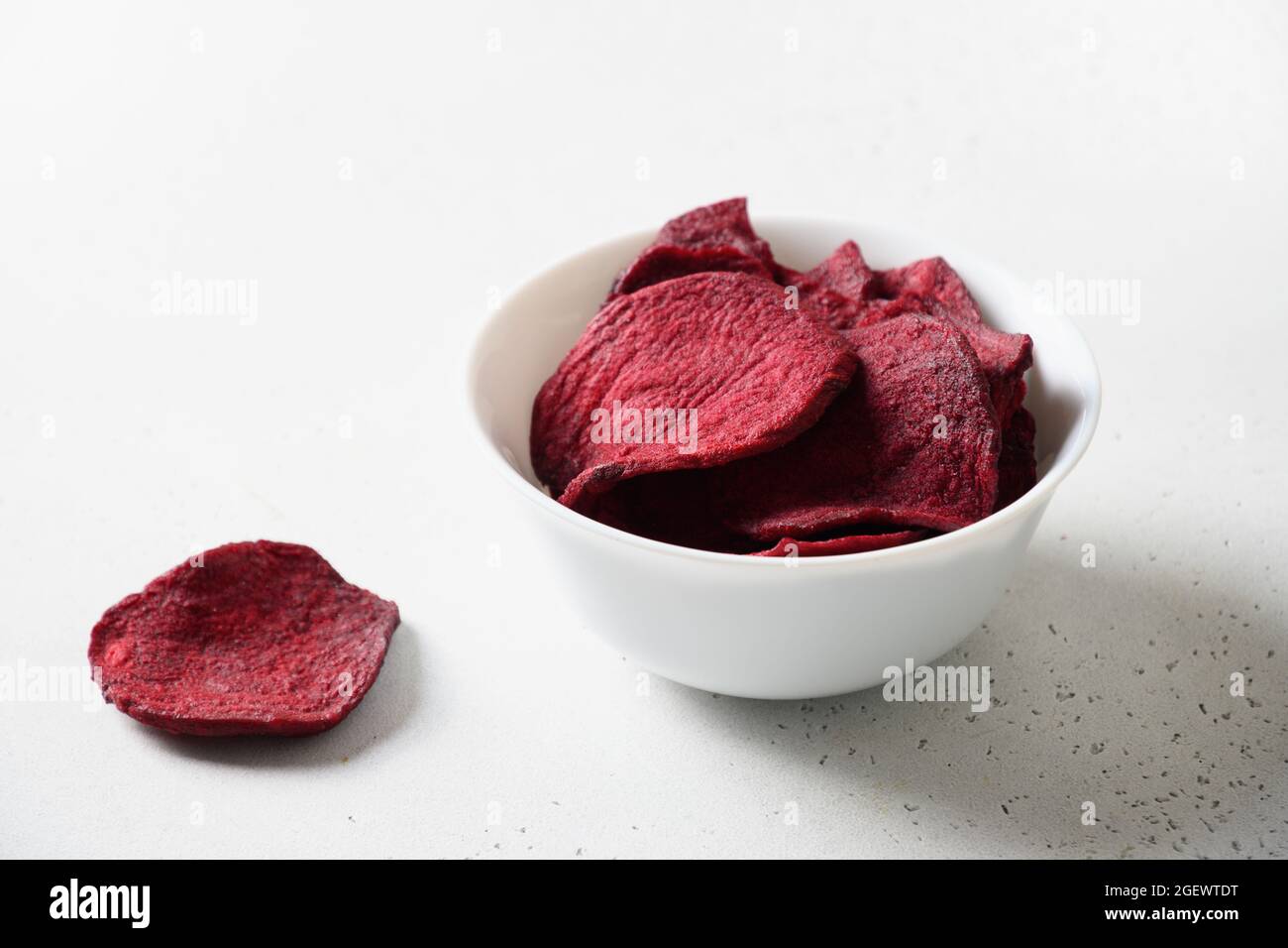 Patatine di barbabietole da verdura in un recipiente bianco su sfondo bianco. Spuntino vegano. Primo piano. Foto Stock Patatine di barbabietole da verdura in un recipiente bianco su sfondo bianco. Spuntino vegano. Primo piano. Foto Stock