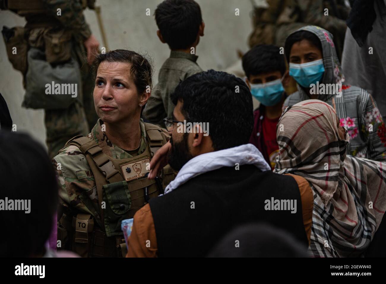 Un Airman degli Stati Uniti con la Joint Task Force-Crisis Response parla con le famiglie che attendono il trattamento durante un'evacuazione all'Aeroporto Internazionale Hamid Karzai, Afghanistan, 20 agosto. I membri del servizio degli Stati Uniti stanno assistendo il Dipartimento di Stato con un'operazione DI evacuazione non combattente (NEO) in Afghanistan. (STATI UNITI Foto del corpo marino di CPL. Davis Harris) Foto Stock