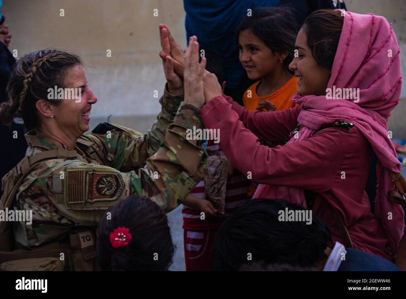 Un Airman degli Stati Uniti con la Joint Task Force-Crisis Response fives alto bambino dopo aver aiutato riunite la loro famiglia all'Aeroporto Internazionale Hamid Karzai, Afghanistan, 20 agosto. I membri del servizio degli Stati Uniti stanno assistendo il Dipartimento di Stato con un'operazione DI evacuazione non combattente (NEO) in Afghanistan. (STATI UNITI Foto del corpo marino di CPL. Davis Harris) Foto Stock