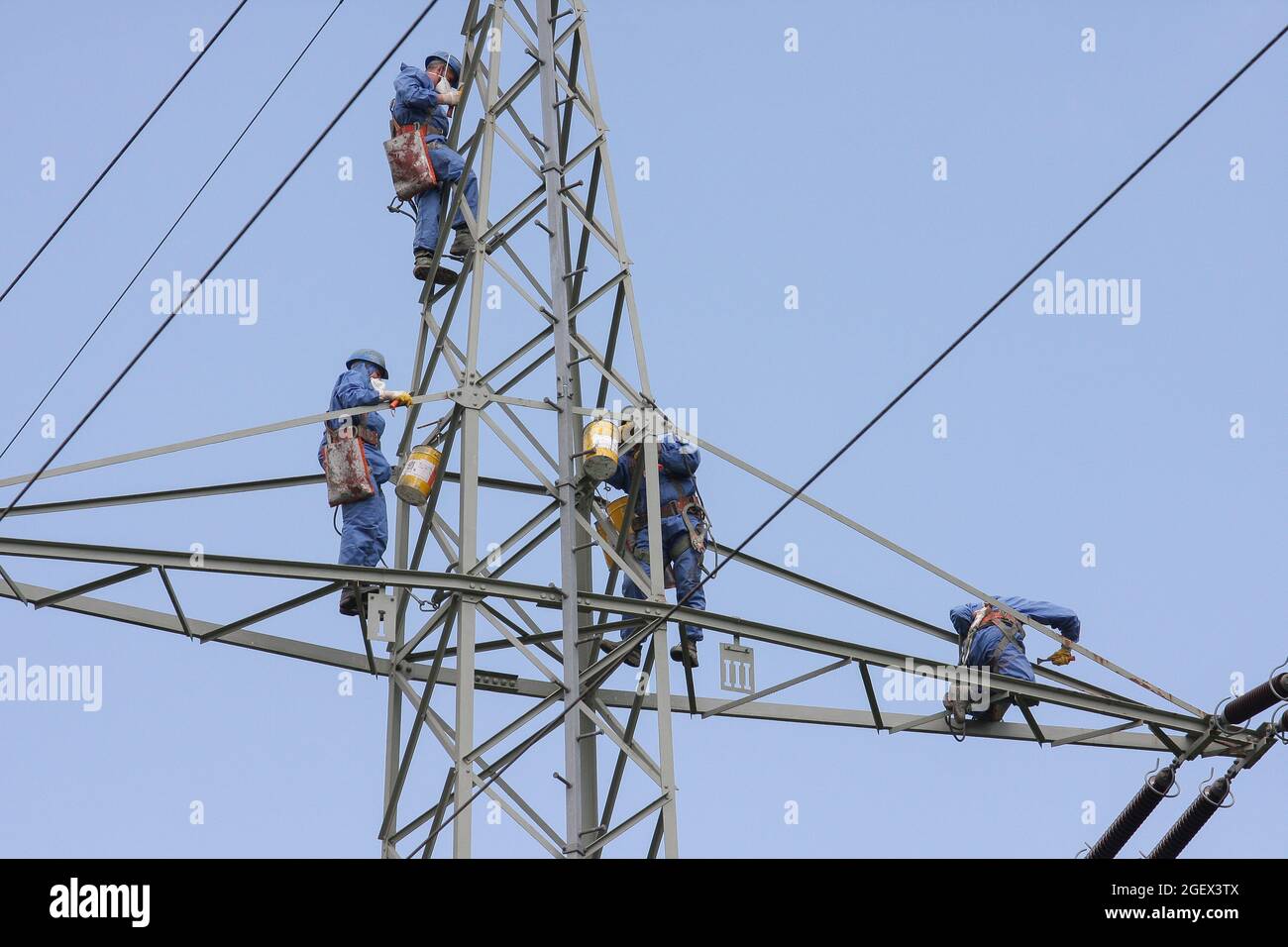 I climber industriali montano corde con casco e indumenti protettivi è fissato con una corda cancellato un palo di potenza di colore grigio. Foto Stock