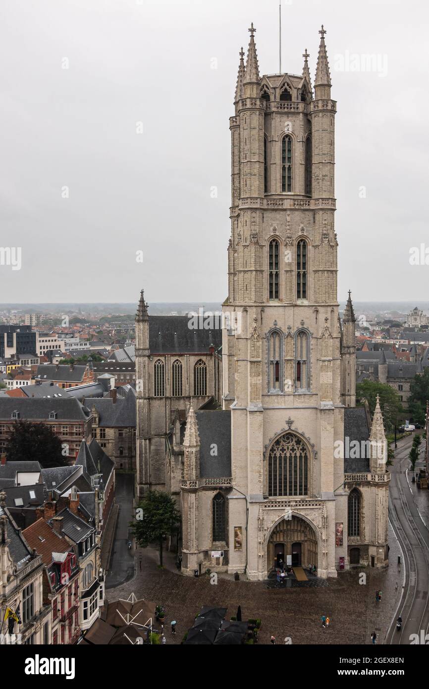 Gent, Fiandre, Belgio - 30 luglio 2021: Primo piano della torre sopra l'ingresso principale nella Cattedrale di Sint Baafs sotto il cielo grigio piovoso. Paesaggio urbano intorno come visto Foto Stock