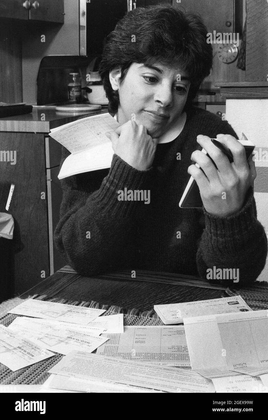 Austin Texas USA, circa 1989: La donna usa la calcolatrice per bilanciare il conto personale di controllo dal suo tavolo da cucina. MR Model rilasciato ©Bob Daemmrich Foto Stock
