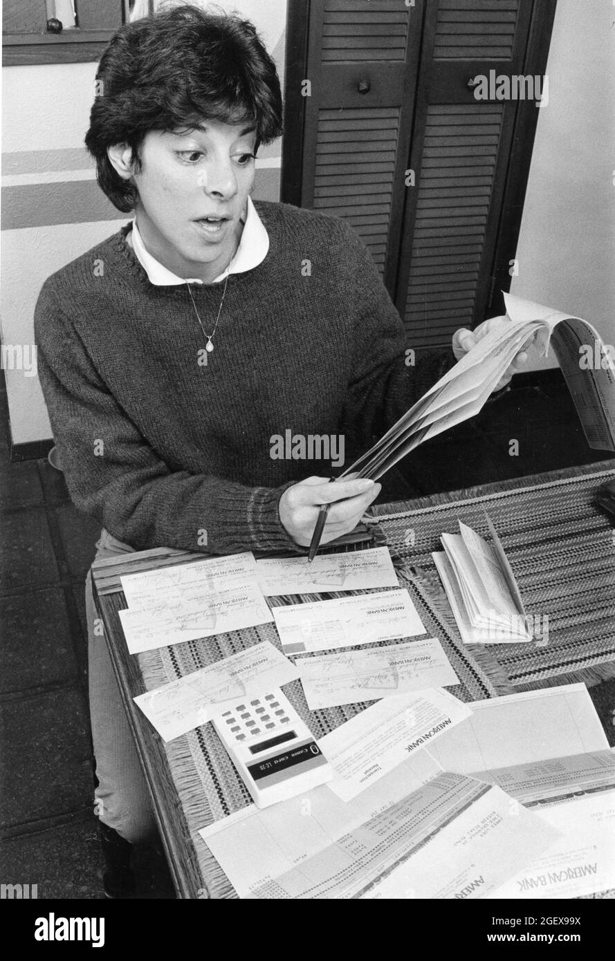 Austin Texas USA, circa 1989: La donna usa la calcolatrice per bilanciare il conto personale di controllo dal suo tavolo da cucina. MR Model rilasciato ©Bob Daemmrich Foto Stock