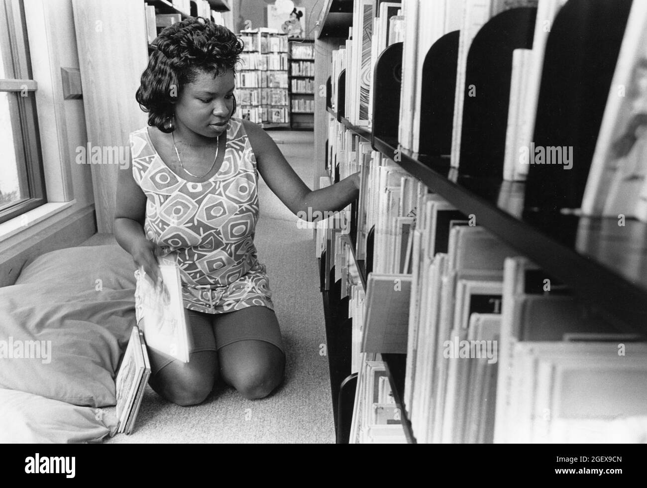 Austin Texas USA, circa 1992: Black femmina High School Senior ha lavoro estivo in biblioteca pubblica; qui ripropone libri. SIGNOR ©Bob Daemmrich Foto Stock