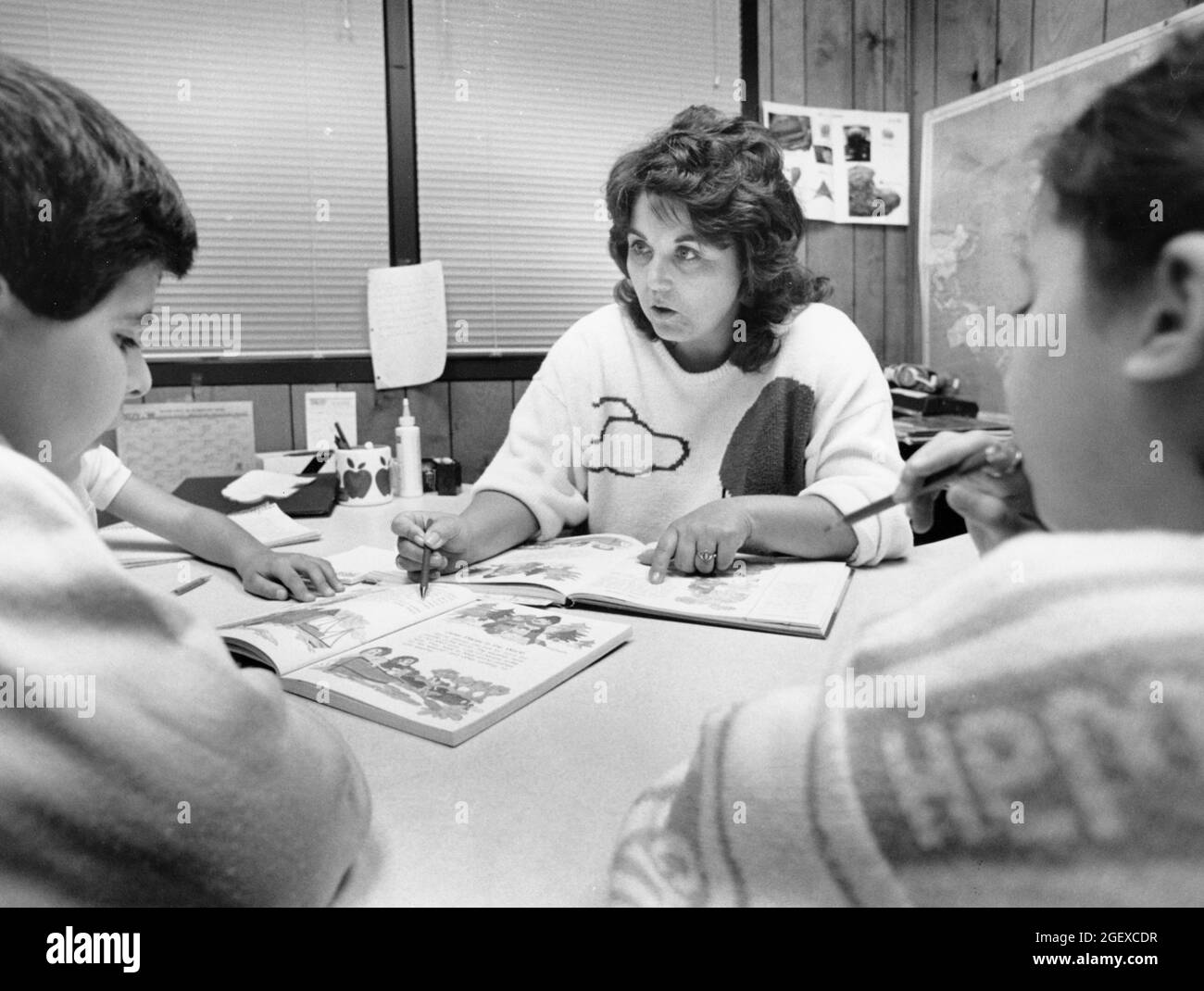 Austin Texas USA, circa 1991: Insegnante di scuola elementare pubblica femminile che lavora con gli studenti di inglese come seconda lingua (ESL) nella sua classe. ©Bob Daemmrich Foto Stock