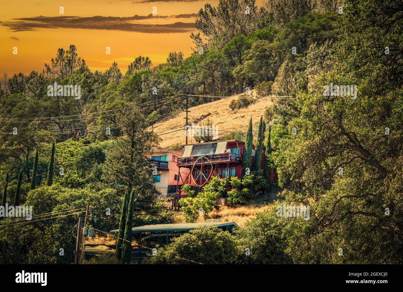 Casa Hippy con enorme segno di pace di fronte sul lato della montagna in California con alberi e il cielo del tramonto Foto Stock