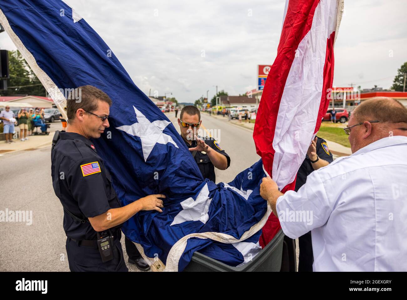 SPENCER, INDIANA - AUGEST 18: I vigili del fuoco alzano una bandiera americana per la processione funeraria del paramedico caduto Brandon Staley il 18 agosto 2021 su W. Morgan Street a Spencer, Indiana. Staley è morto per un attacco di cuore mentre lavorava come paramedico per Owen County EMS. Staley aveva appena risposto a un incidente stradale e si trovava in un'ambulanza con i sopravvissuti agli incidenti che li aiutavano a raggiungere un ospedale quando egli stesso si ammalò. Foto Stock