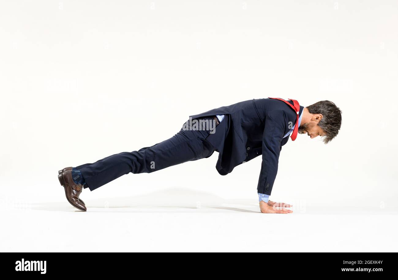 Uomo d'affari in abito elegante allenarsi con push-up in una vista laterale completa su bianco in un concetto di fitness e stile di vita sano e attivo Foto Stock