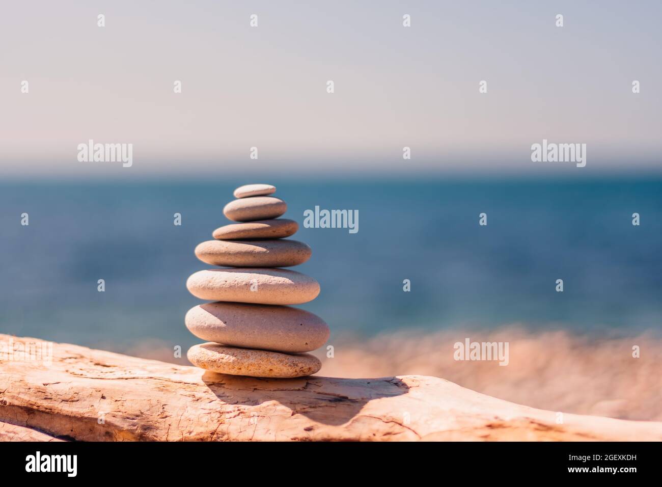 Equilibrata piramide di ciottoli sulla spiaggia in una giornata di sole. Abstract Sea bokeh sullo sfondo. Messa a fuoco selettiva. Pietre Zen sulla spiaggia di mare, meditazione Foto Stock