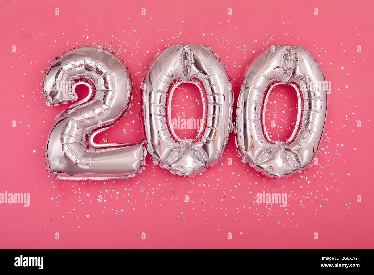 Da sopra di palloncini d'argento lucido che dimostrano numero 200 su sfondo rosa con glitter sparsi Foto Stock