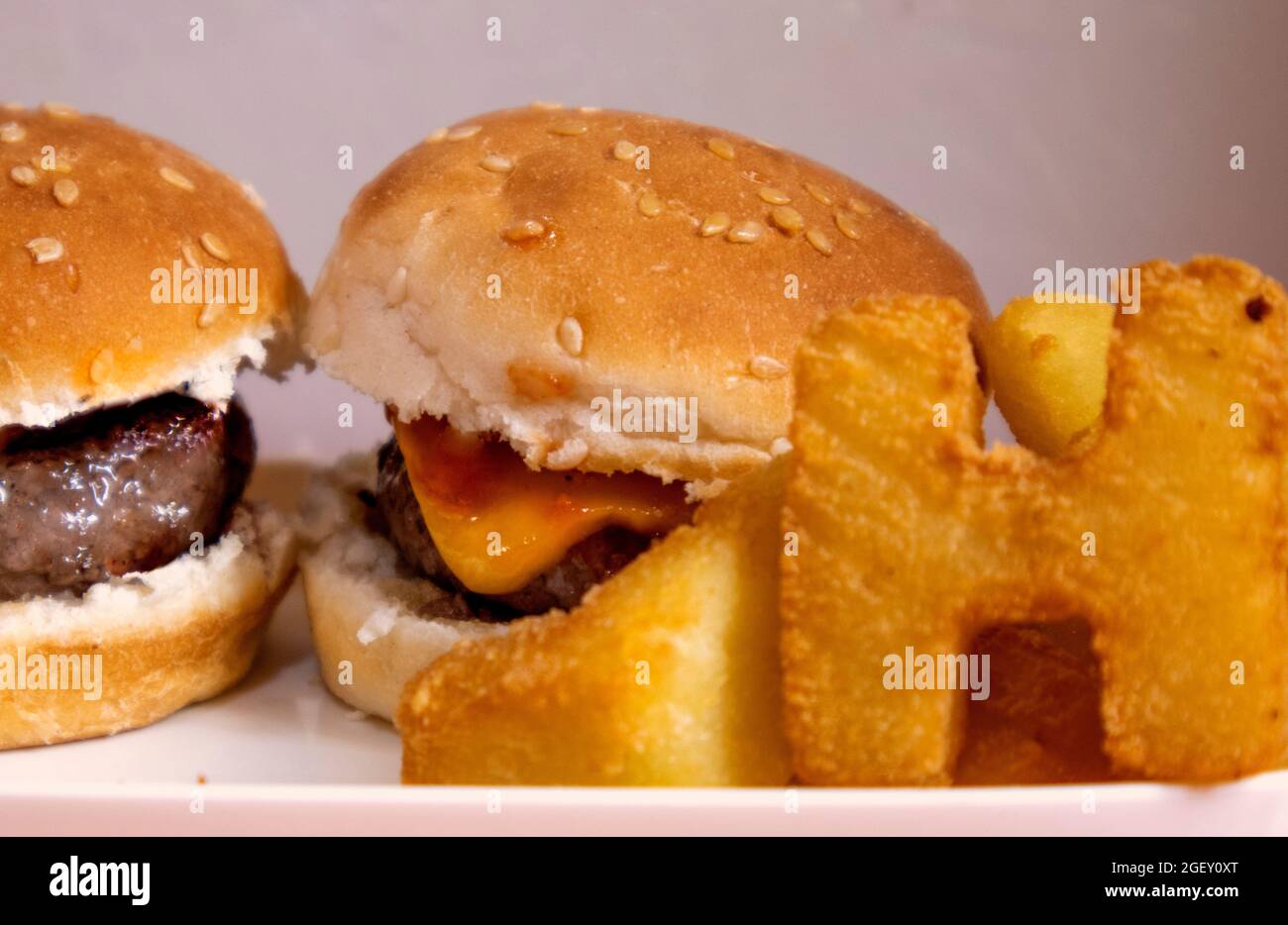 mini hamburger in primo piano accompagnati da patatine fritte a forma di lettere. Foto Stock