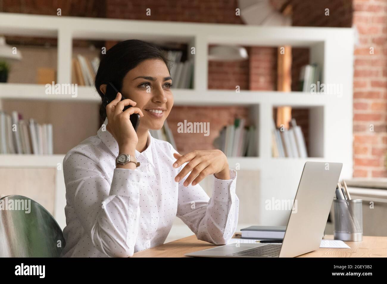 La donna d'affari indiana tiene la conversazione commerciale principale dello smartphone con il cliente dell'azienda Foto Stock