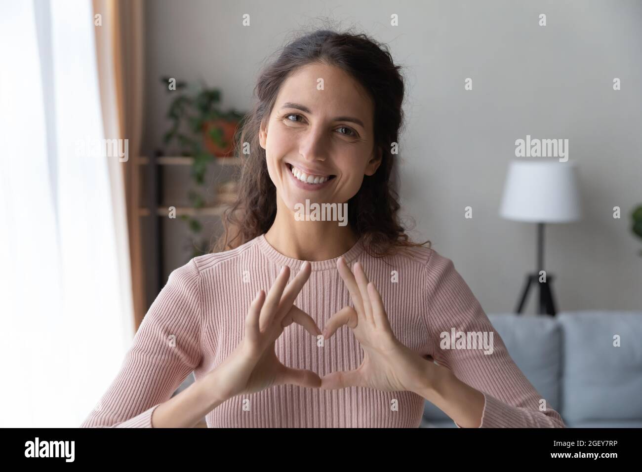 Testa ritratto sorridente donna unire le dita facendo il simbolo del cuore Foto Stock