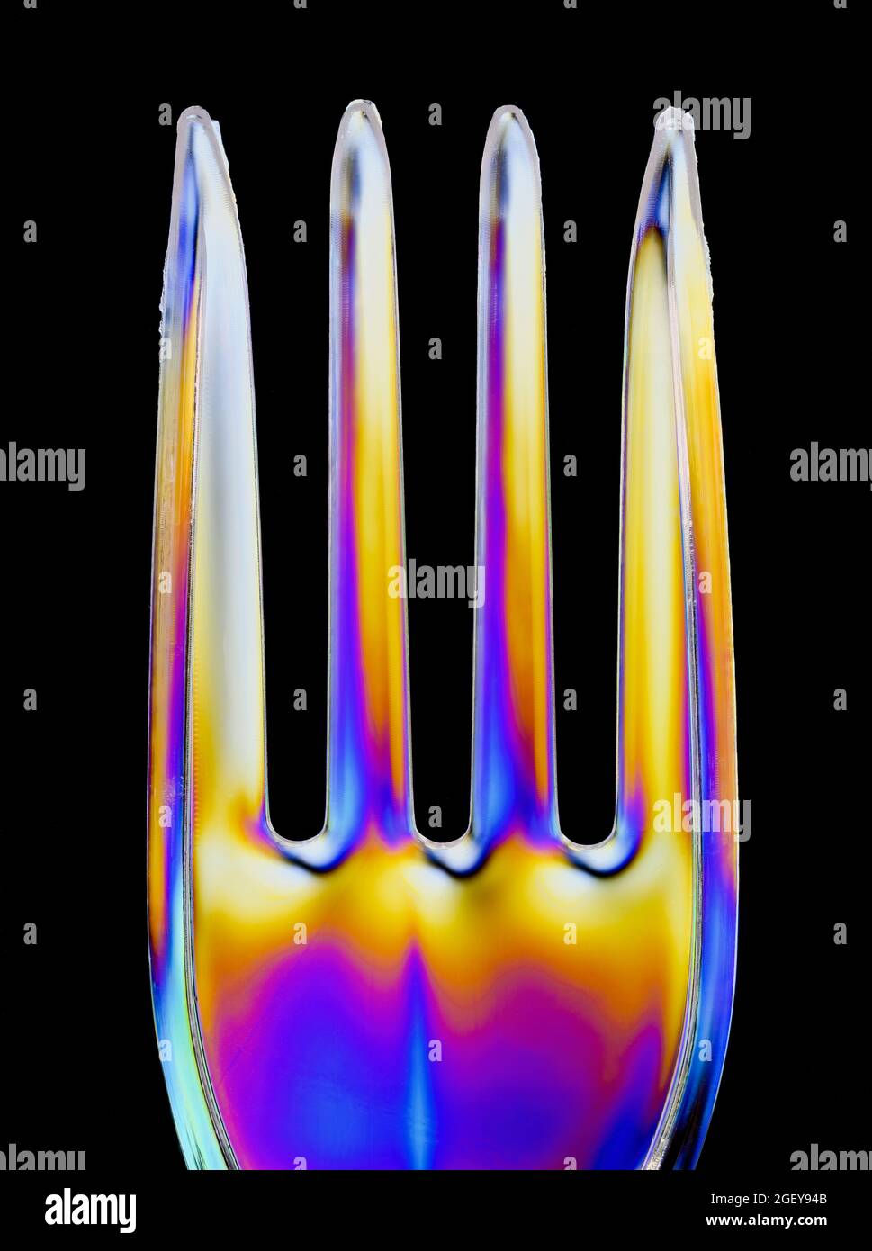 I motivi colorati si formano su una forcella in plastica trasparente causata dalla rifrazione della luce polarizzata Foto Stock