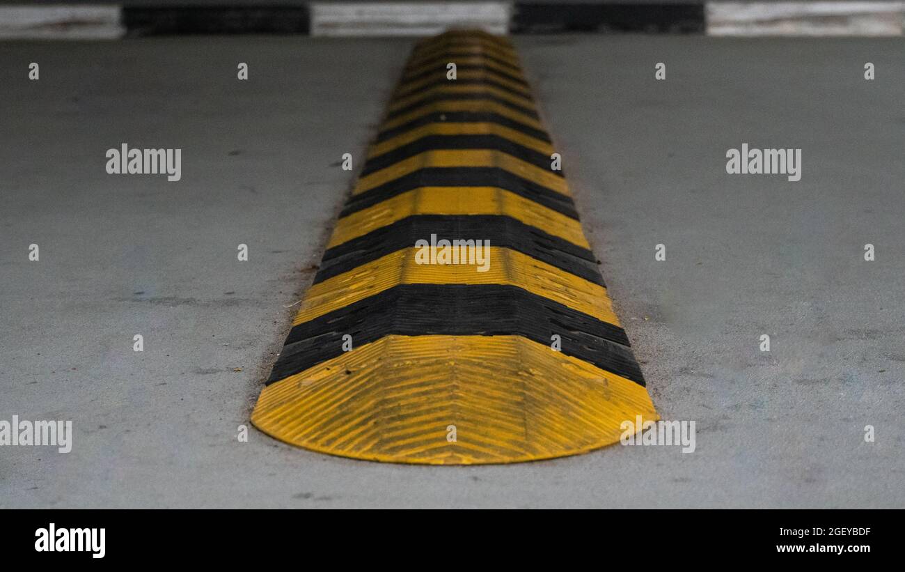 La velocità di sicurezza del traffico si è ridotta su una strada asfaltata in un'area di parcheggio. I dossi di velocità (o interruttori di velocità) sono il nome comune per una famiglia di calmanti del traffico de Foto Stock