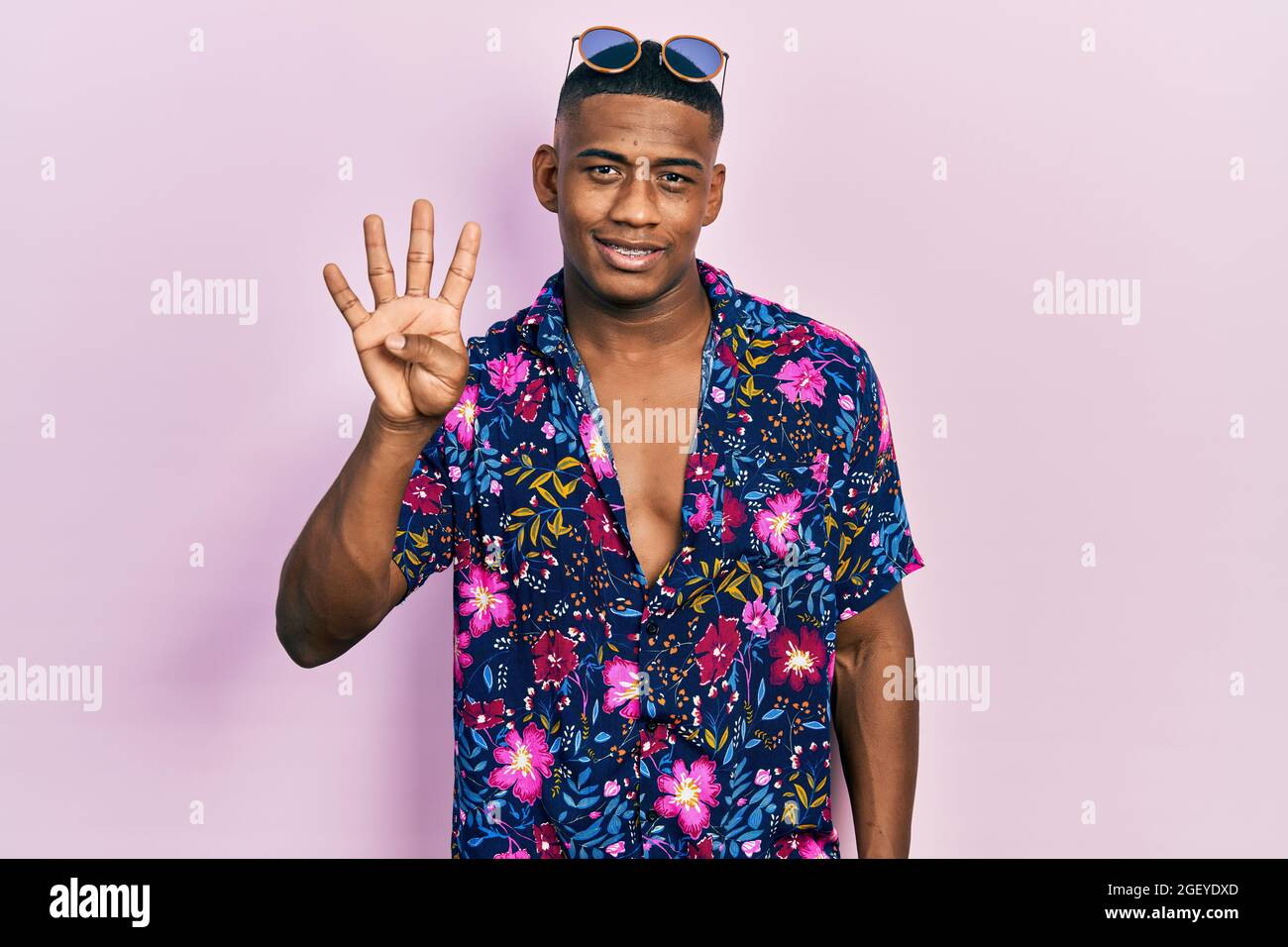 Giovane uomo nero che indossa una camicia hawaiana e occhiali da sole che  mostra e punta con le dita numero quattro sorridendo sicuro e felice Foto  stock - Alamy