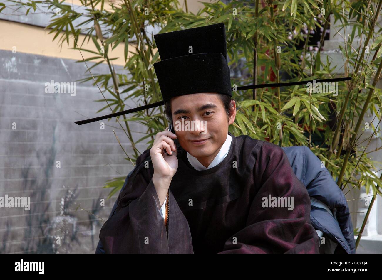 Attore in costume in stand-by durante le riprese di una storica produzione televisiva cinese. Hengdian World Studios studio-città con i suoi enormi palazzi è il più grande studio-complesso in Asia e quindi ha guadagnato il soprannome 'Chinawood'. Foto Stock