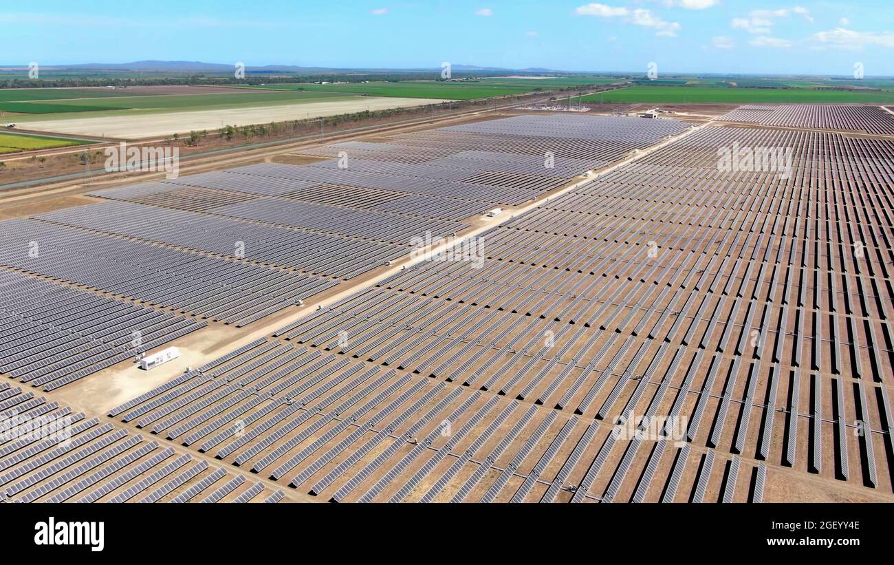 vista aerea del drone di una vasta fattoria di energia solare con campi agricoli in background campagna. Foto Stock