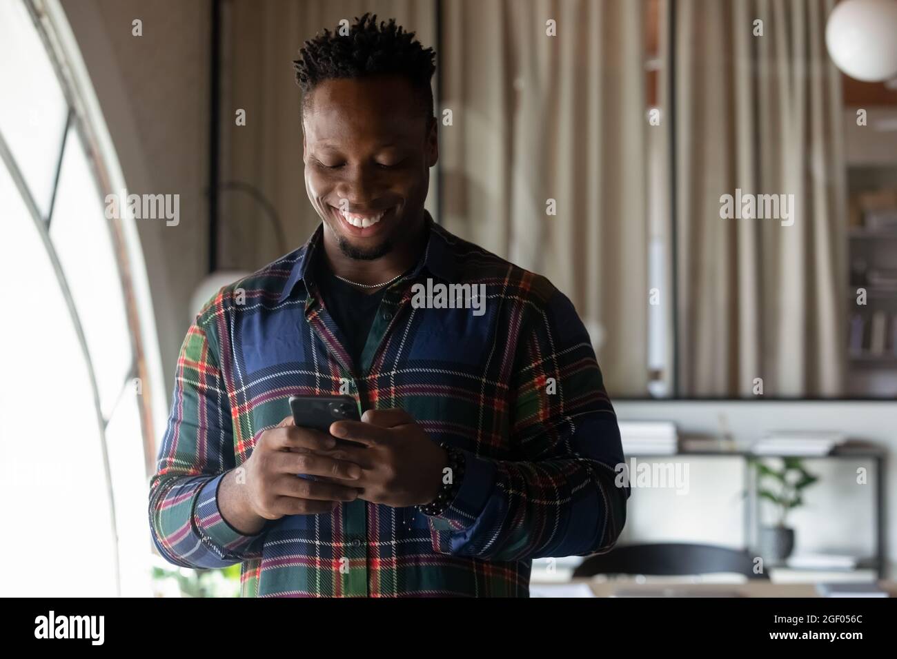 Sorridente uomo afroamericano utilizzare cellulare comunicare online Foto Stock