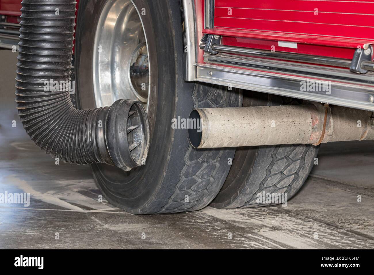Tubo di scarico del veicolo antincendio con sistema di aspirazione dei fumi diesel. Concetto di controllo delle emissioni, salute e sicurezza dei vigili del fuoco in casa dei fuochi d'artificio Foto Stock