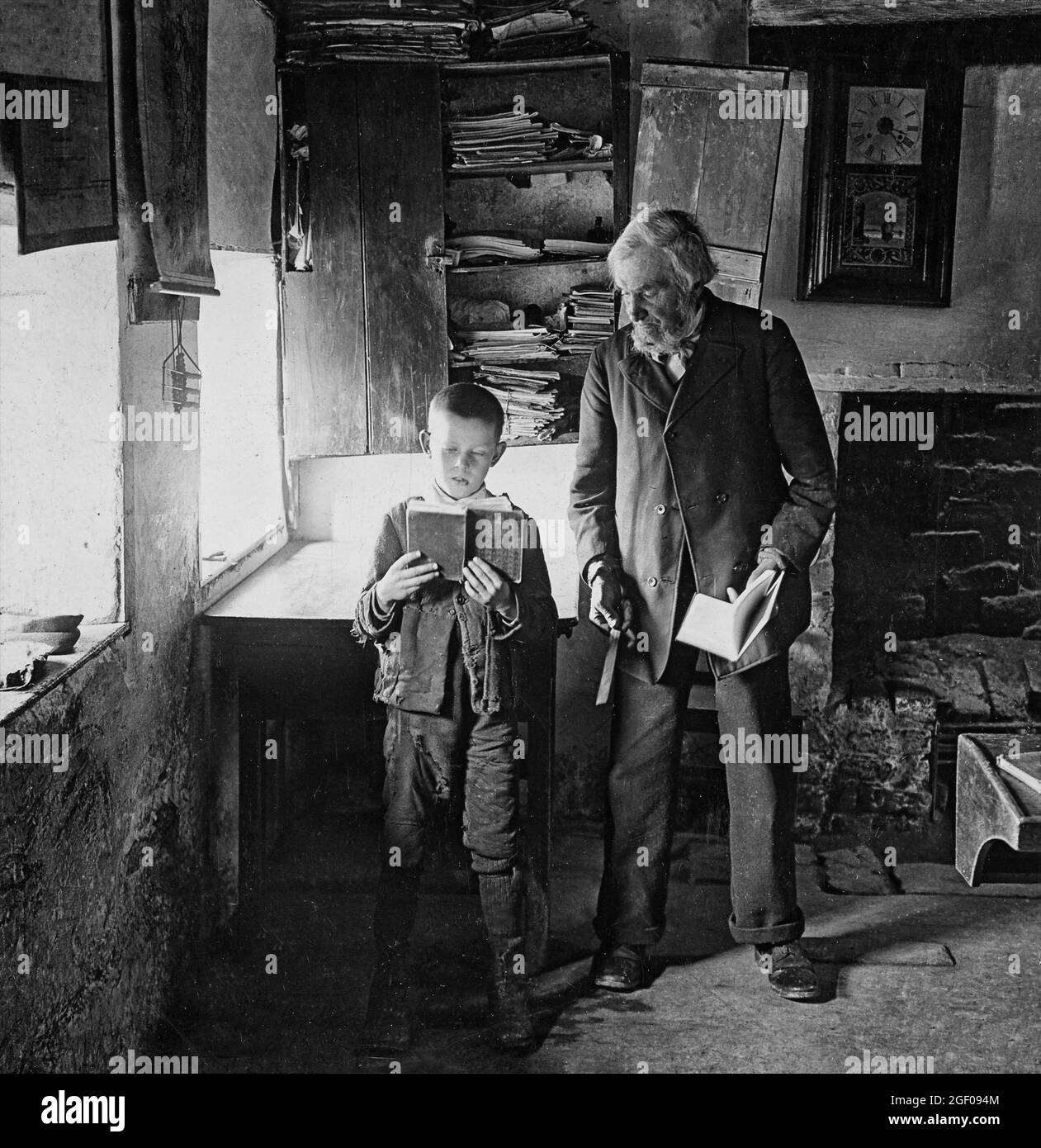 Insegnante e un giovane ragazzo che legge un libro ad una scuola nazionale del XX secolo nella contea di Monaghan, Irlanda Foto Stock