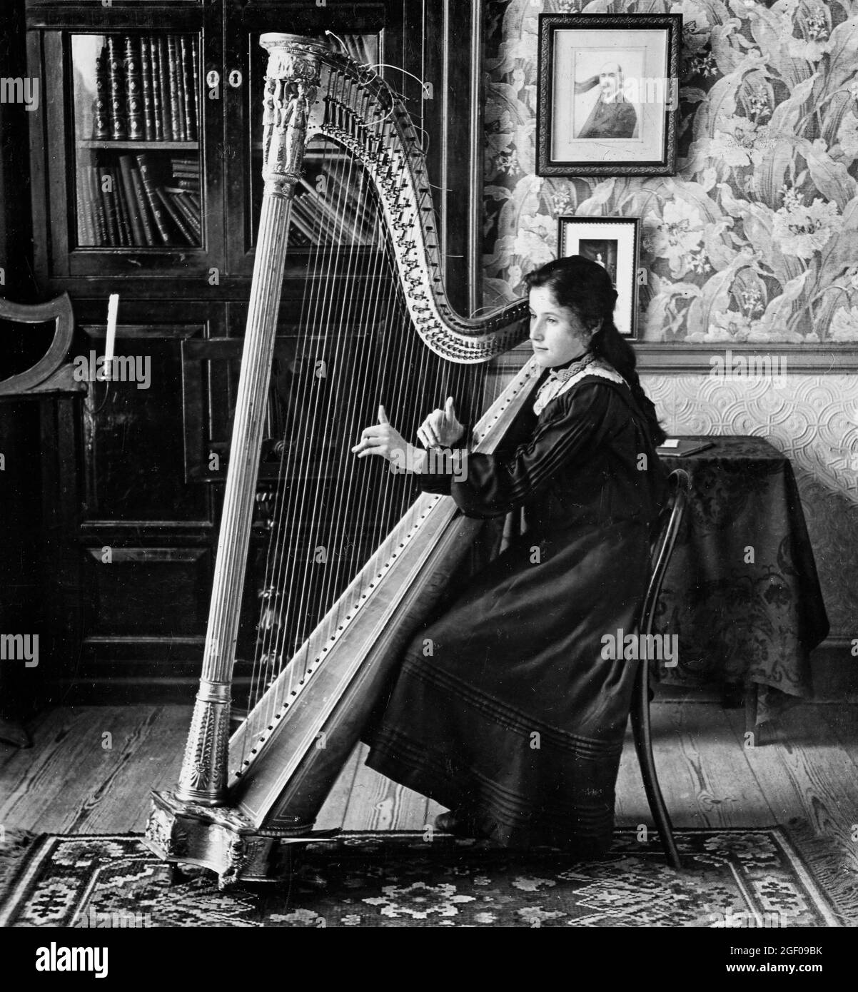 Scena del 20esimo secolo di giovane donna da una famiglia ricca che gioca un'arpa nella casa di campagna irlandese Foto Stock