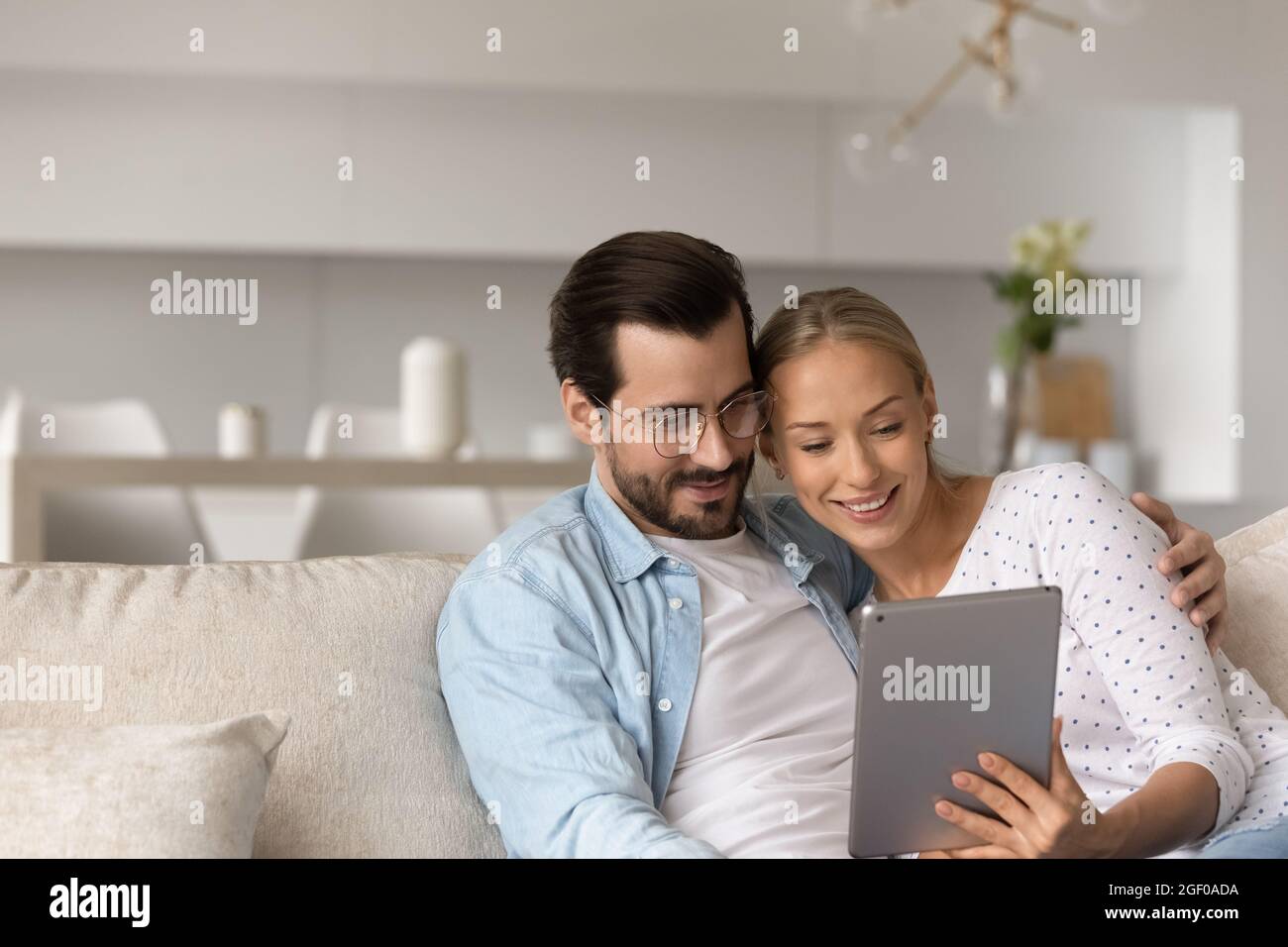 Felice coppia millennial rilassarsi a casa, abbracciare sul divano Foto Stock