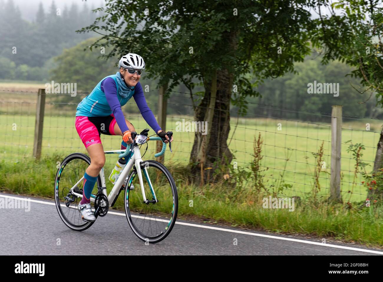 Fort Augustus, Scozia, Regno Unito. 22 agosto 2021. I ciclisti che prendono parte all'Etape Loch Ness hanno chiuso la strada ciclistica sportiva seguendo un percorso a 360 gradi di 66 miglia / 106 km intorno a Loch Ness, Scozia, partendo e finendo a Inverness. Migliaia di sterline saranno raccolti dai partecipanti al Macmillan Cancer Support, l'evento ufficiale di beneficenza. Questa immagine mostra un partecipante che raggiunge il punto di metà strada vicino a Fort Augustus. Cliff Green/Alamy Foto Stock