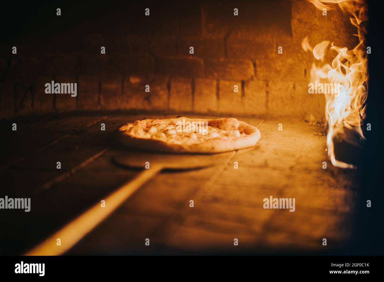 Pizza appena fatta che è messa in forno caldo del fuoco del legno della pizza Foto Stock