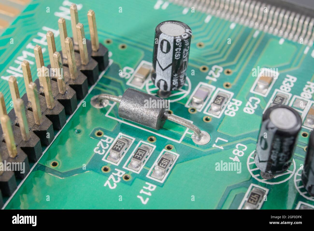 Primo piano del componente in ferrite nera a foro passante simile a un resistore sulla scheda a circuito stampato + resistori più piccoli oblunghi SM / a montaggio superficiale. Foto Stock