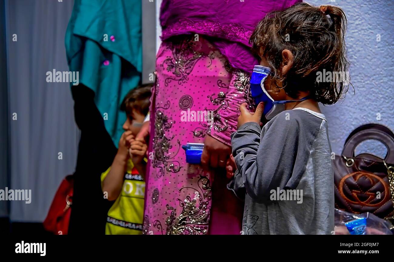 Una famiglia di evacuati afghani attende in linea presso il Joint Processing Readiness Centre della base aerea di Ramstein, Germania, 20 agosto 2021. La base aerea di Ramstein fornisce alloggi sicuri e temporanei per gli sfollati dall'Afghanistan come parte del Refuge Operation Allees. Questa operazione sta facilitando l'evacuazione rapida e sicura dei cittadini statunitensi, dei richiedenti di visti speciali per immigrati e di altri afghani a rischio dall'Afghanistan. FOTO DI CREDITO: US DoD via American PhotoArchive Foto Stock