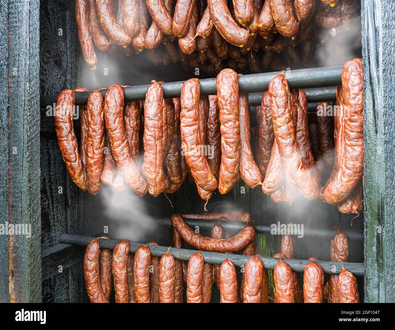 Fumo di salami piccanti kielbasa in legno fumo dettaglio casa. Primo piano di salumi affumicati caldi di carne di maiale e manzo appeso all'interno di affumiceria fatta in casa. Foto Stock