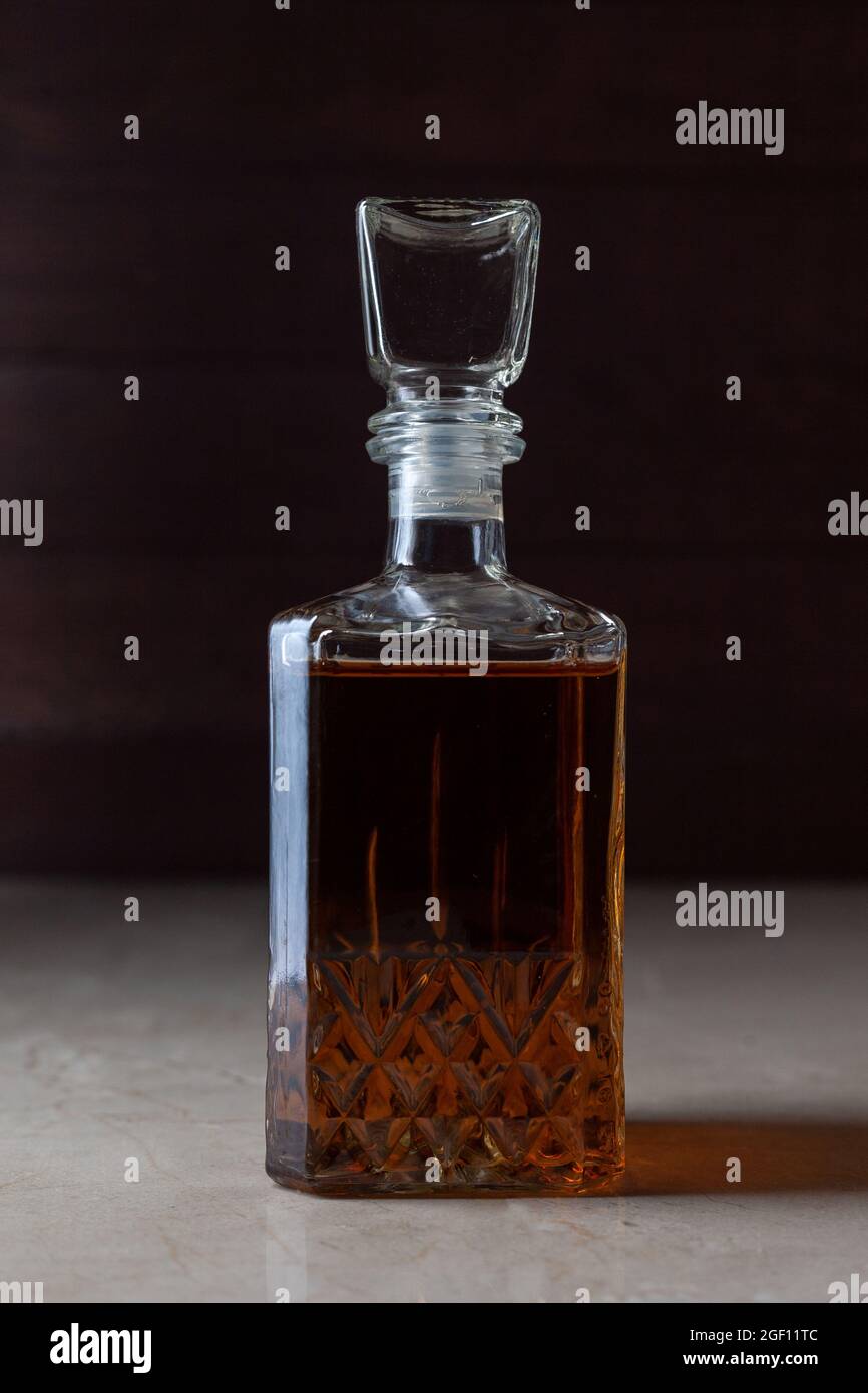 Vaso d'epoca con alcol e ombra. Può essere whiskey, cognac, brandy, sherry o calvados su tavola di marmo di umore scuro. Foto Stock