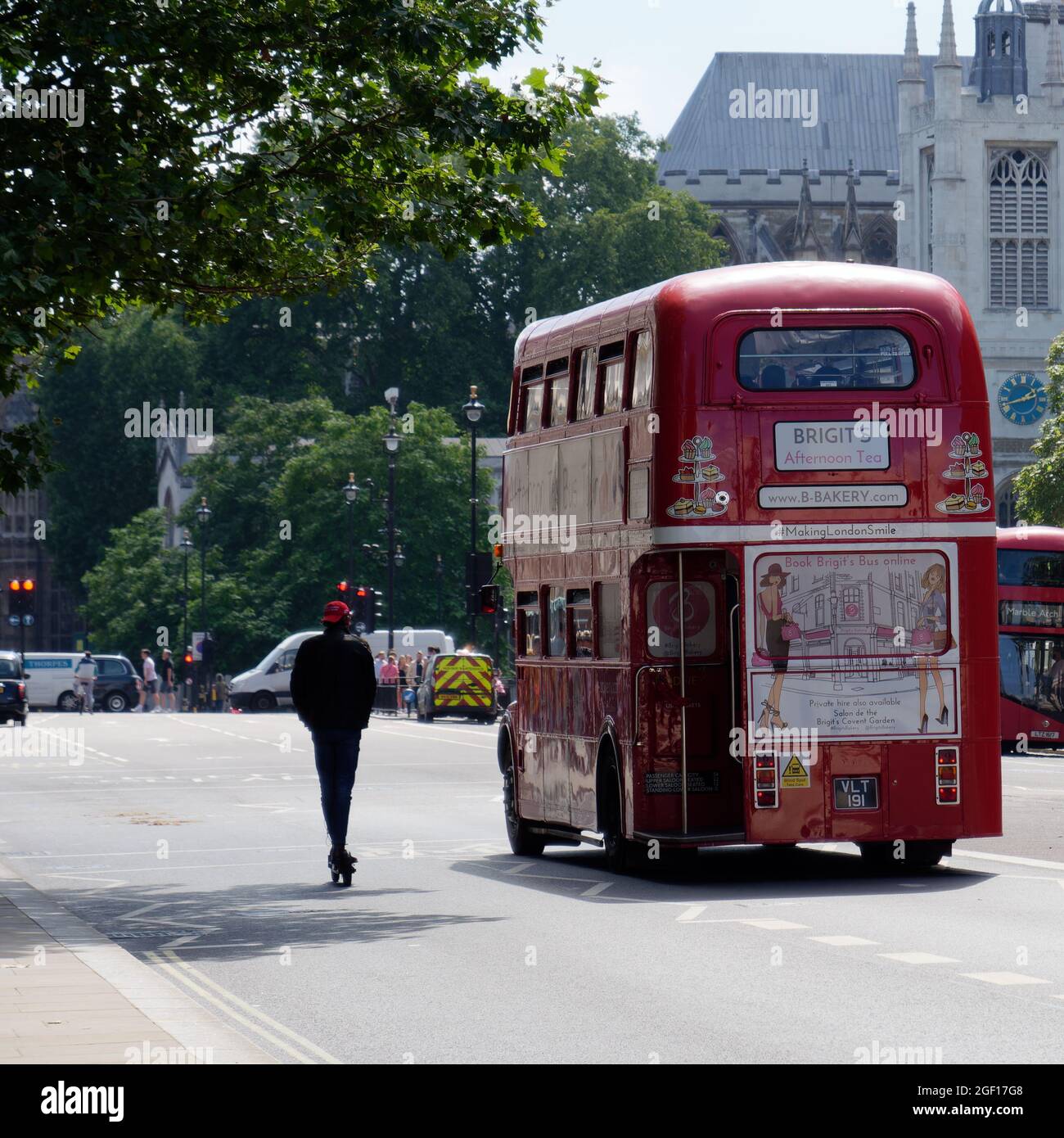 Londra, Greater London, Inghilterra, 10 2021 agosto: Brigits pomeriggio Tea bus con un giovane a cavallo di uno scooter elettrico accanto ad esso a Whitehall. Foto Stock