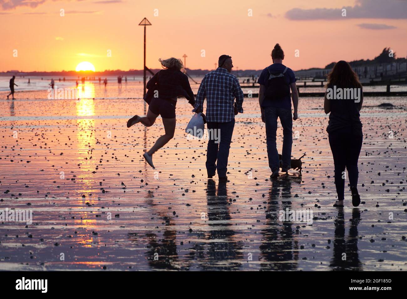 East Wittering, Sussex, UK, 22 agosto 2021: Quando il tramonto è arrivato alla bassa marea, i colori del cielo si riflettevano lungo la spiaggia in East Wittering Sussex. Mentre il tempo è destinato a diventare più caldo per alcuni giorni, la gente del posto e i villeggianti hanno colto l'opportunità di nuotare, pescare, giocare a cricket e camminare i loro cani. Anna Watson/Alamy Live News Foto Stock