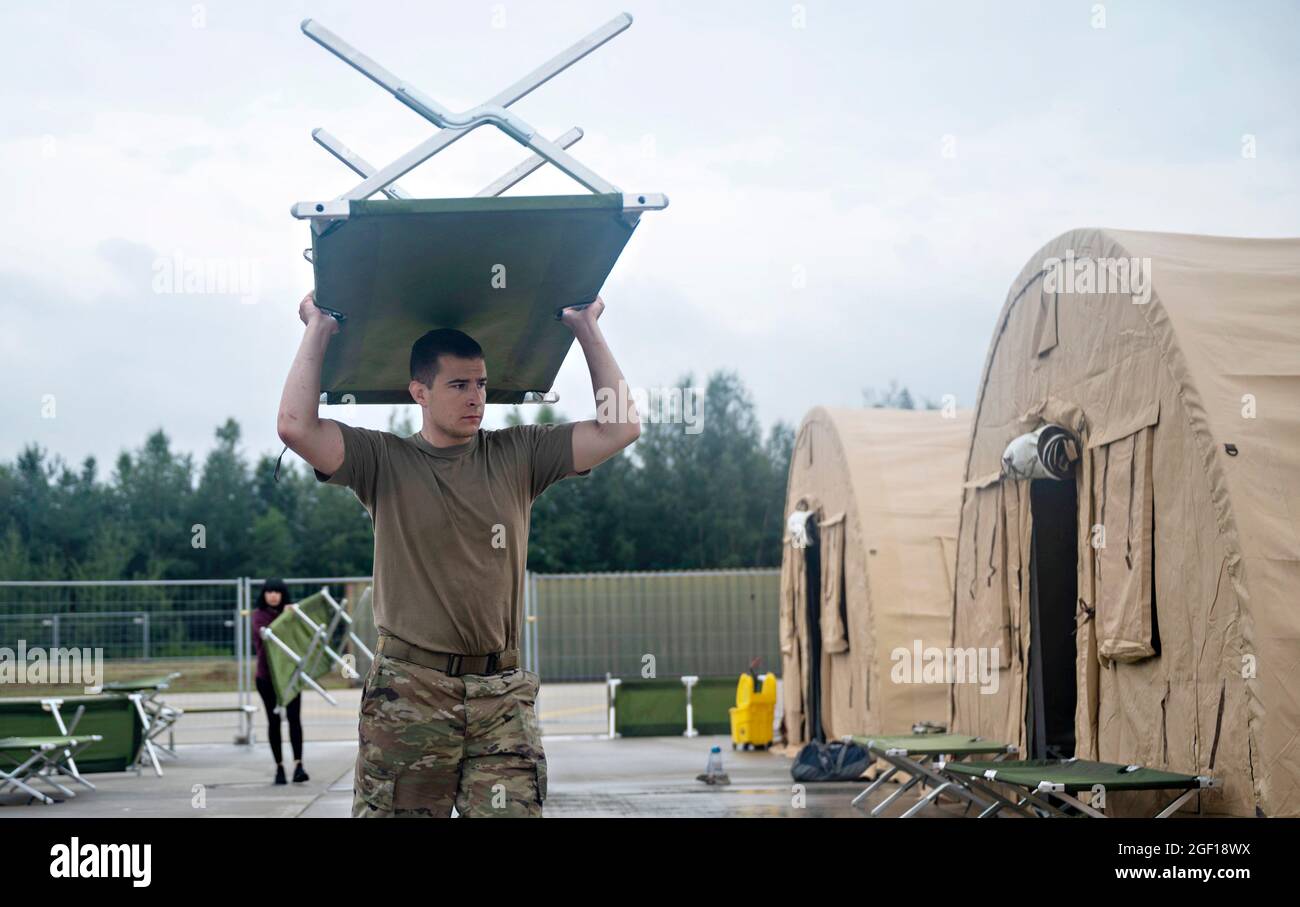 Ramstein Miesenbach, Germania. 22 agosto 2021. US Air Force SSgt. Jared Caton, 86th Materiel Maintenance Squadron, trasporta una culla ad un alloggiamento pod per i rifugiati afghani alla base aerea di Ramstein 22 agosto 2021 a Ramstein-Miesenbach, Germania. La base aerea di Ramstein fornisce alloggio temporaneo per gli sfollati dall'Afghanistan come parte del Refuge Operation Allees. Credit: Planetpix/Alamy Live News Foto Stock