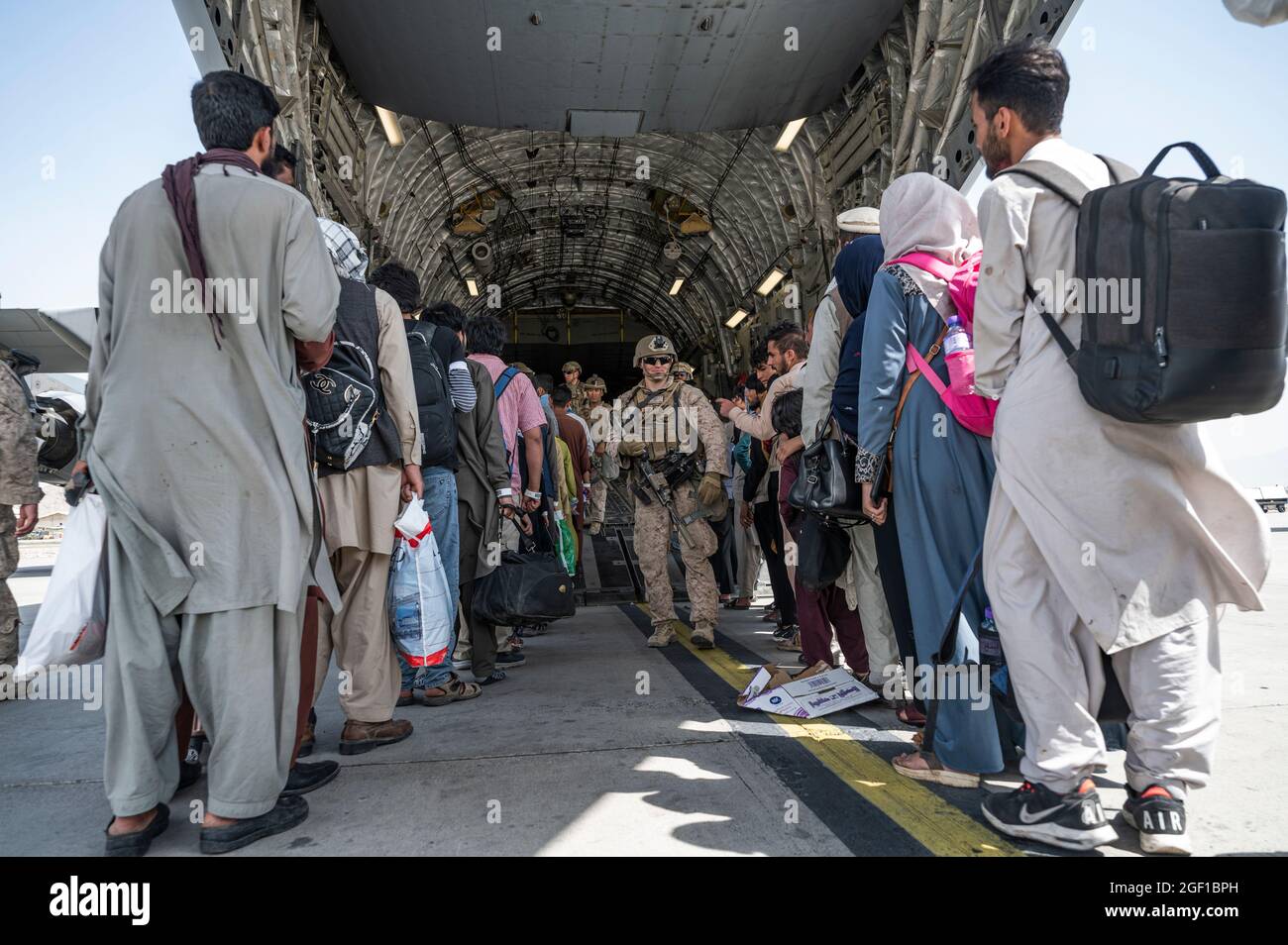 Gli Stati Uniti Airmen e la guida dei marines degli Stati Uniti hanno qualificato gli evacuati a bordo di una forza aerea degli Stati Uniti C-17 Globemaster III a sostegno dell'evacuazione dell'Afghanistan all'aeroporto internazionale Hamid Karzai (HKIA), Afghanistan, 21 agosto 2021. Il Dipartimento della Difesa si impegna a sostenere il Dipartimento di Stato degli Stati Uniti nella partenza del personale civile statunitense e alleato dall'Afghanistan e a evacuare gli alleati afghani per la sicurezza. (STATI UNITI Foto delle forze aeree di Senior Airman Brennen Lege) Foto Stock