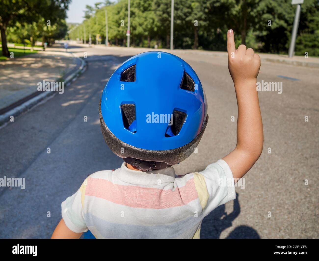 Bambino in casco con mano sollevata. Campo estivo. Attività sportive Foto Stock