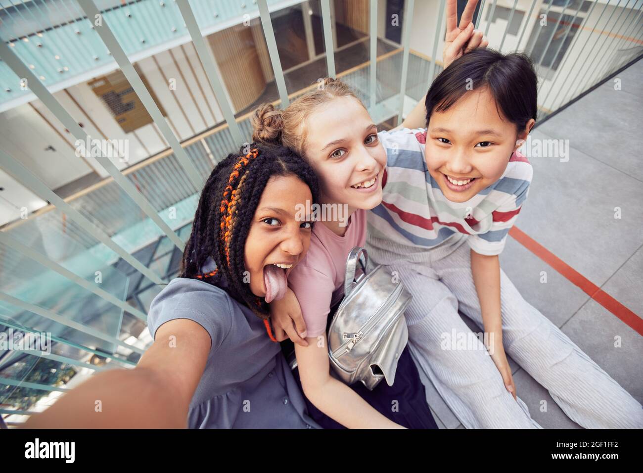 Vista ad angolo alto POV a diversi gruppi di scolari che prendono insieme selfie Foto Stock