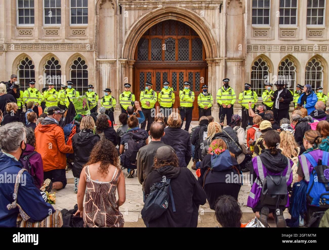 Londra, Regno Unito. 22 agosto 2021. I manifestanti si inginocchiano mentre i poliziotti sorvegliano l'ingresso dell'edificio Guildhall durante la dimostrazione. I manifestanti di estinzione della ribellione si sono riuniti a Guildhall per la cerimonia di apertura della loro campagna di due settimane contro la ribellione impossibile, che si concentrerà sulla città di Londra, il centro finanziario della capitale. (Foto di Vuk Valcic/SOPA Images/Sipa USA) Credit: Sipa USA/Alamy Live News Foto Stock
