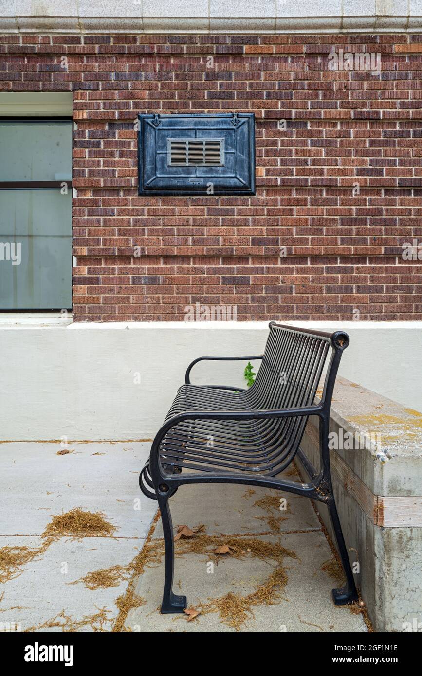 Un banco di metallo nero davanti ad un muro di mattone Foto Stock