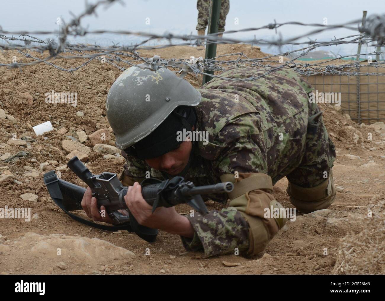 Un tirocinante di base dell'esercito nazionale afghano striscia sotto il filo spinato mentre negozia un corso di ostacolo al Centro di addestramento militare regionale di Gardez nella provincia di Paktya, Afghanistan, 25 febbraio 2013. Il tirocinante sta partecipando a un corso di formazione di base di nove settimane, che si laureerà a marzo circa 600 nuovi soldati ANA. (STATI UNITI Esercito foto di SPC. Tianna Waite/rilasciato) Foto Stock