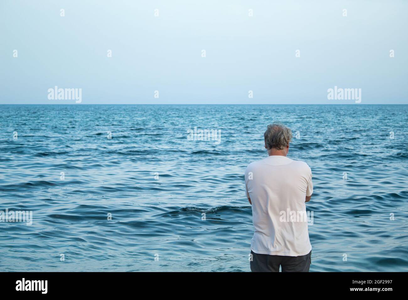 vista da dietro di uomo maturo con capelli grigi godendo sulla spiaggia Foto Stock